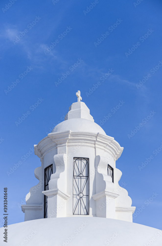 White tower with catholic cross on top in the roof of the Cathedral in Leon city, Nicaragua. Blue sky with copy space.