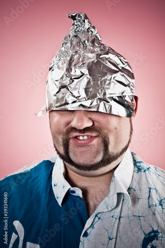 Canvas Print Studio photo of a goofy looking man wearing a tin foil hat on dark pink background