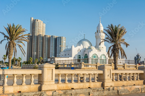 A white Al Rahmah mosque and palm trees with background of tall building located at Jeddah Corniche, 30 km coastal resort area of Jeddah city.Saudi Arabia photo