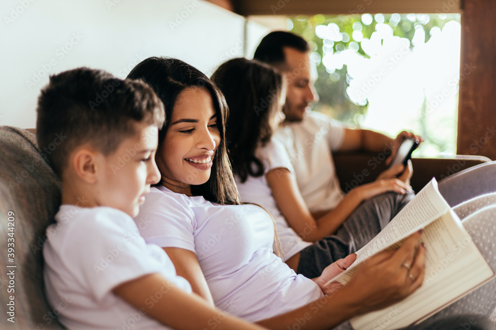 Latin family enjoying the day together at home. Family reading together on the couch in the morning.