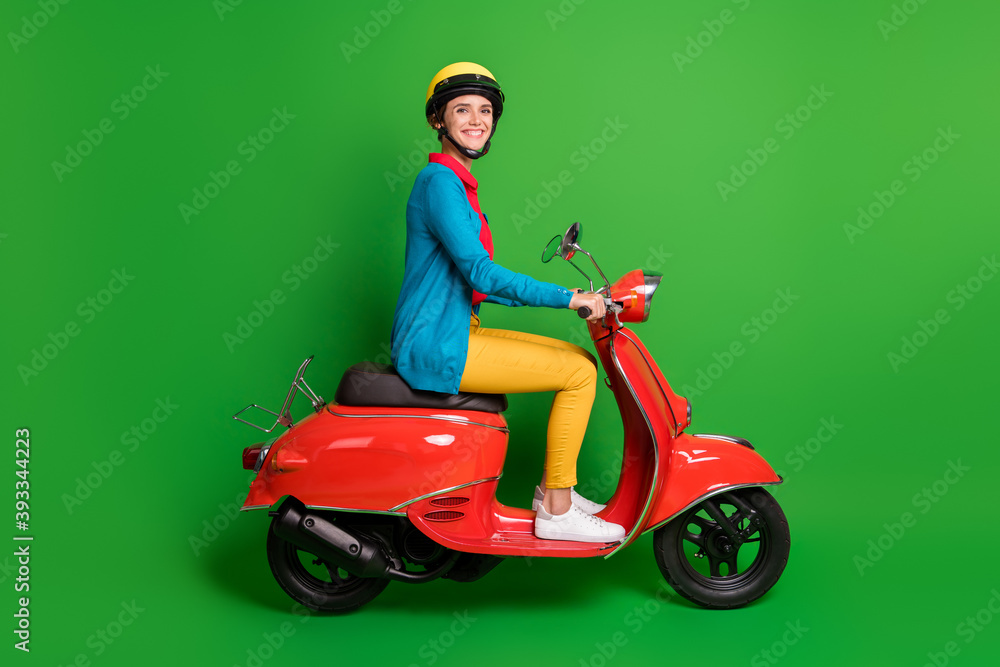 Full size profile side photo of young cheerful smiling girl look camera ride red motorcycle isolated on green color background Full size profile side photo of young cheerful smiling girl look camera ride red motorcycle isolated on green color background