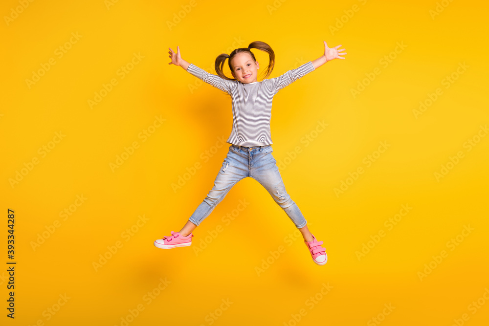 Full size photo of young happy positive little girl child kid jump raise hands up isolated on yellow color background