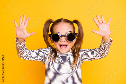 Portrait of young happy fooling careless smiling little girl kid hands search up wear funky sunglasses isolated on yellow color background