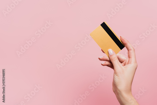 cropped view of woman holding credit card isolated on pink photo