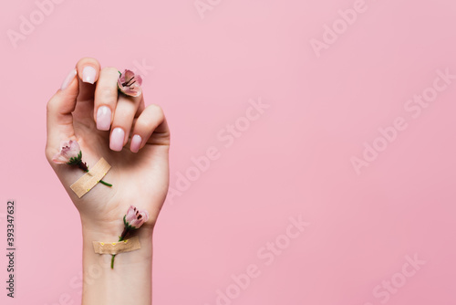 plasters with flowers on female hand isolated on pink