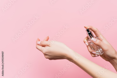 cropped view of woman holding bottle with luxury perfume isolated on pink photo