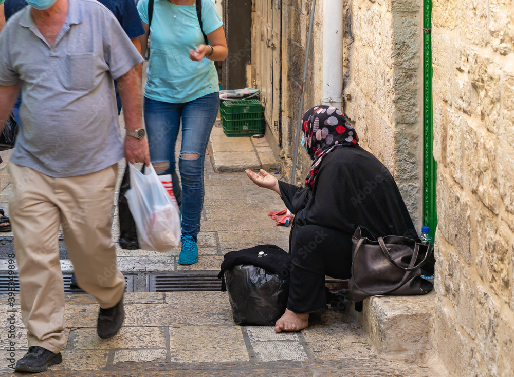 Elderly arab muslim woman sitting on the Beit HaBad street and begging for alms in the Muslim part of the old city of Jerusalem, Israel