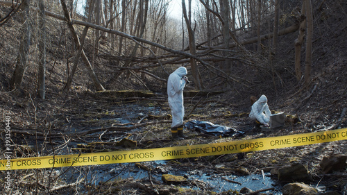 Detectives are collecting evidence in a crime scene. Forensic specialists are making expertise. Police investigation in a forest.