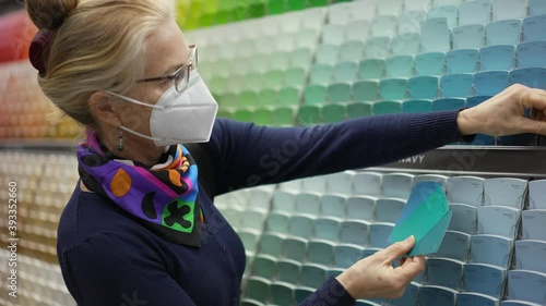 Closeup of woman wearing face mask looking at paint chips in a hardware store. Concept of cornonavirus shopping experience. photo