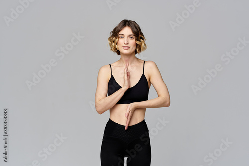 A slender woman is gesturing with her hands on a gray background Sport Fitness figure