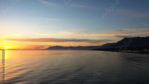 sunset view of Marbella sea at sunset, shot with gimbal on a boat moving out to Mediterranean sea paddle surfer in the distance photo