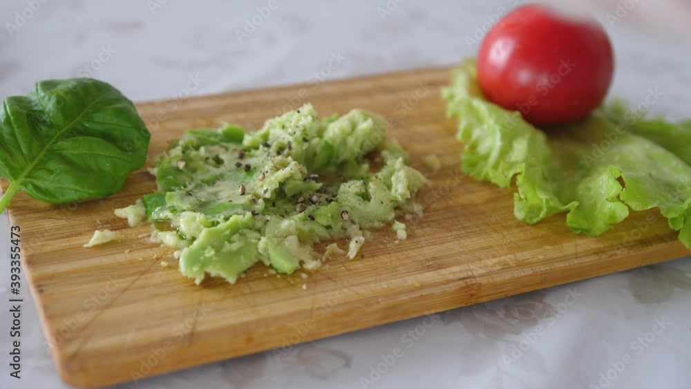 Peppering of mashing avocado with black pepper on a board. Healthy food cooking Peppering of mashing avocado with black pepper on a board. Healthy food cooking