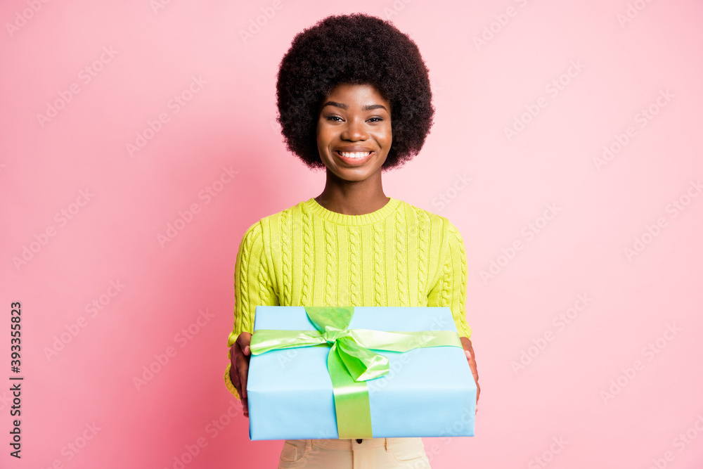 Photo portrait of woman holding gift box in two hands isolated on pastel pink colored background Photo portrait of woman holding gift box in two hands isolated on pastel pink colored background