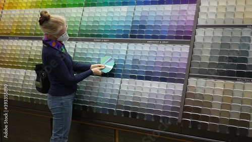 Closeup of woman wearing face mask looking at paint chips in a hardware store. Concept of cornonavirus shopping experience. photo