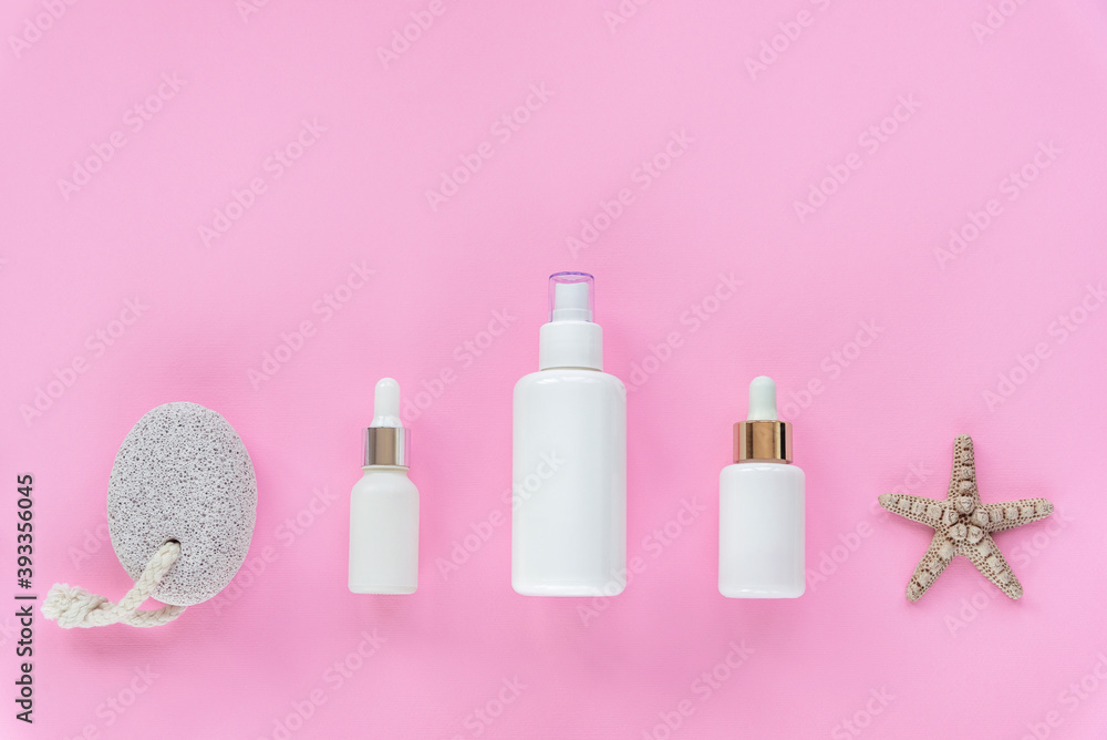 Natural organic beauty skincare products. Cosmetic oils in white unbranded bottles, pumice stone on pink background Natural organic beauty skincare products. Cosmetic oils in white unbranded bottles, pumice stone on pink background