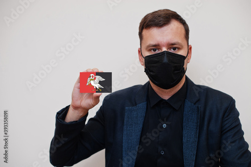 Man wear black formal and protect face mask, hold Buckinghamshire flag card isolated on white background. United Kingdom counties of England coronavirus Covid concept. photo