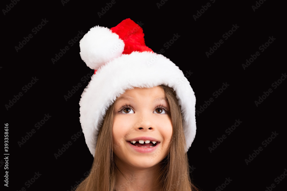 A beautiful little girl in a Christmas hat looks up. A beautiful little girl in a Christmas hat looks up.