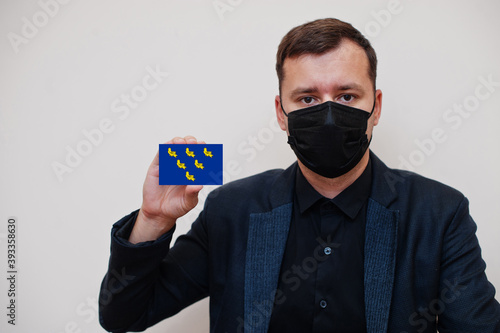 Man wear black formal and protect face mask, hold Sussex flag card isolated on white background. United Kingdom counties of England coronavirus Covid concept. photo