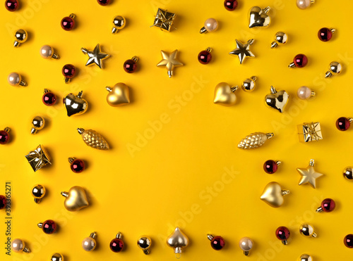 Christmas modern composition. Golden decorations on yellow background. Flat lay, top view, copy space.
