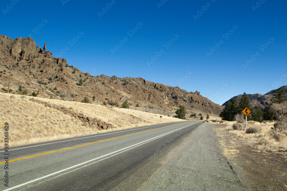 Empty road with clear blue sky and mountains surrounding. 