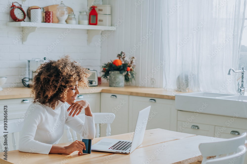 © wifesun - Lady with perfect dark skin holding credit card and inserting bank information for online shopping sits near laptop closeup © wifesun - Lady with perfect dark skin holding credit card and inserting bank information for online shopping sits near laptop closeup
