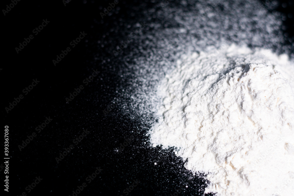 On the right side of the screen is a handful of white flour on a dark background. The left part is free. On the right side of the screen is a handful of white flour on a dark background. The left part is free.