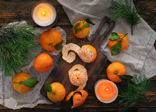 Tangerines with leaves on a wooden table  next to candles and pine branches  Christmas still life