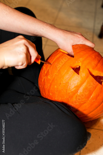 Close up of a woman's hands carving a Jack O' lantern for Halloween.