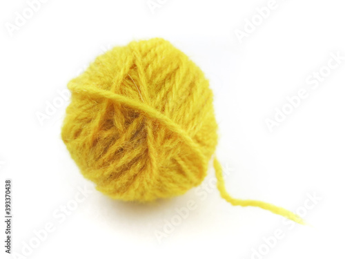 A ball of yellow woolen knitting threads on a white background.   