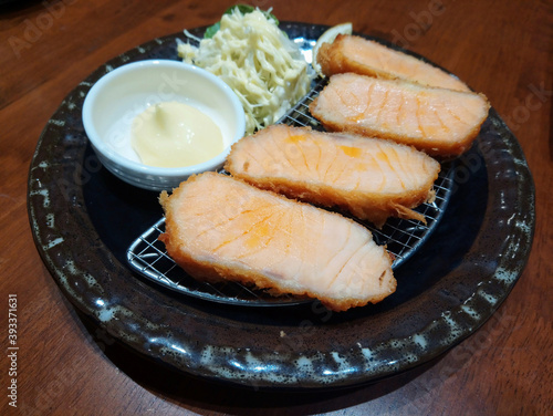 Fried salmon fish Japanese food with coleslaw vegetable and sauce dip served on black plate