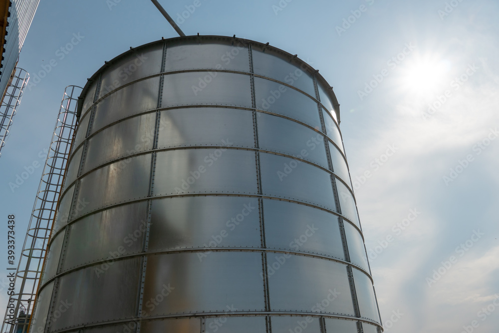 silver silos on agro manufacturing plant for processing drying cleaning and storage of agricultural products, flour, cereals and grain. Large iron barrels of grain. Granary elevator silver silos on agro manufacturing plant for processing drying cleaning and storage of agricultural products, flour, cereals and grain. Large iron barrels of grain. Granary elevator
