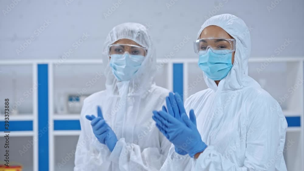 African american scientists in hazmat suits and latex gloves clapping hands African american scientists in hazmat suits and latex gloves clapping hands