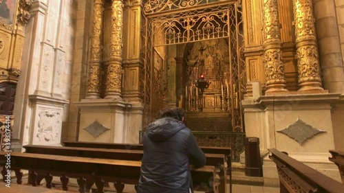 Man praying in front of golden altar in church in Porto