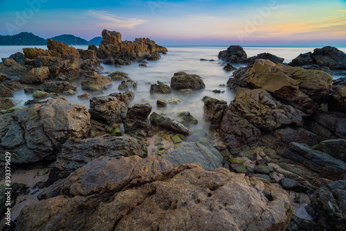 Beautiful rocks by the beach, splashed by the sea. With the sky and the sunset view on the landscape background long exposure shots.
