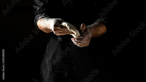 Man sprinkling flour over fresh dough for pizza  Cooking bread. Kneading the Dough  men hands with flour splash