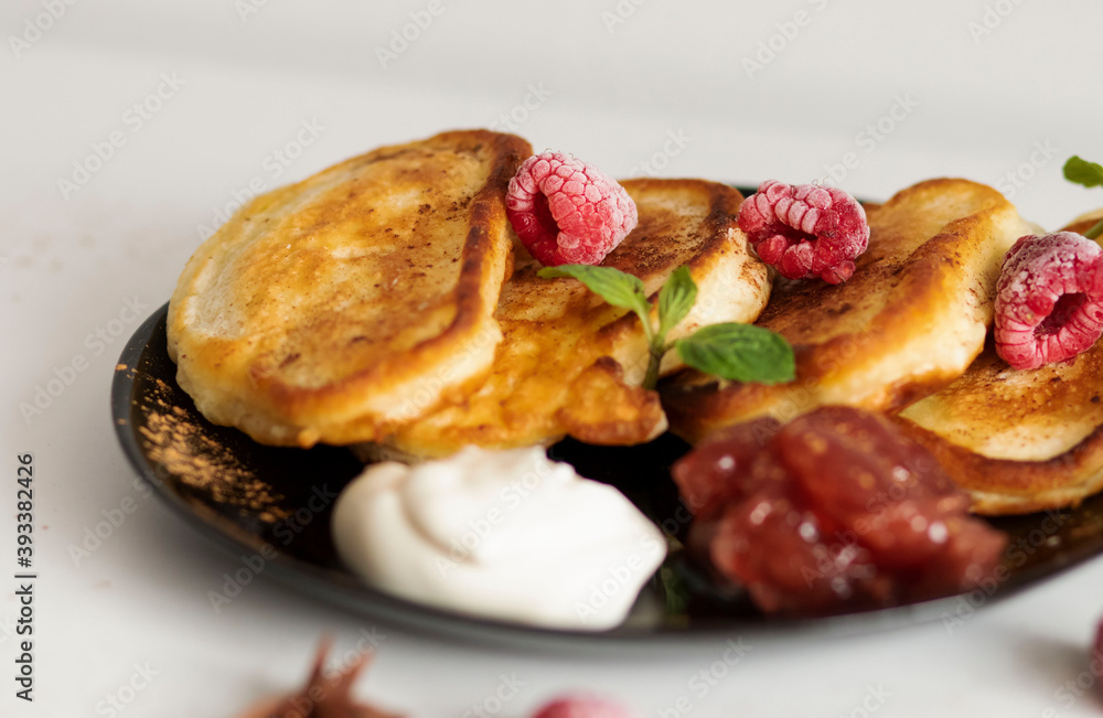 Breakfast with pancakes on plates, sour cream and pavidl. Pancakes are on a white table and the guy is holding in his hands. Breakfast with pancakes on plates, sour cream and pavidl. Pancakes are on a white table and the guy is holding in his hands.