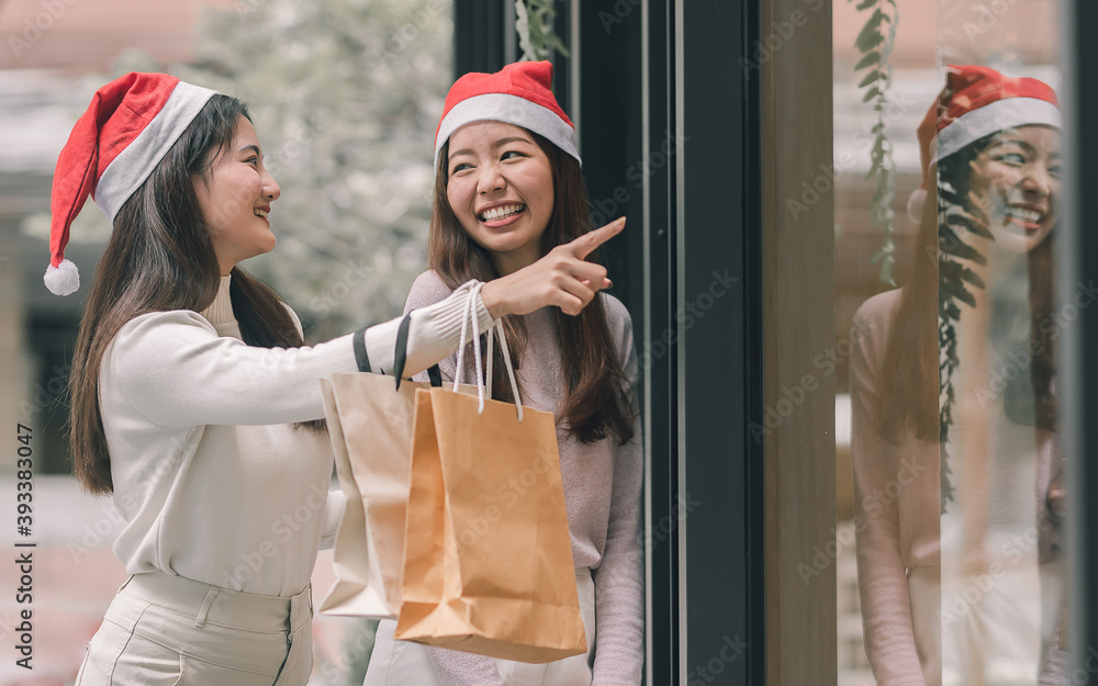 Obraz premium Two women doing window shopping and holding bags in christmas season