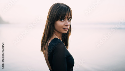 Young woman in black clothes looking at camera near sea Free Download Young woman in black clothes looking at camera near sea - GFXLoad