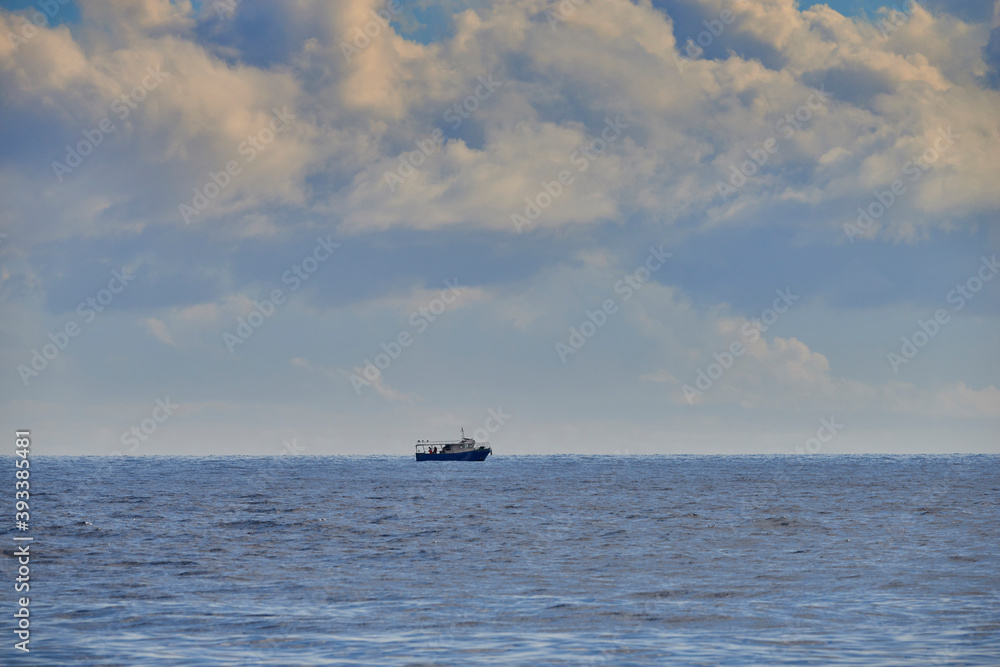 a fishing boat in the middle of the sea in the clouds on a beautiful autumn day