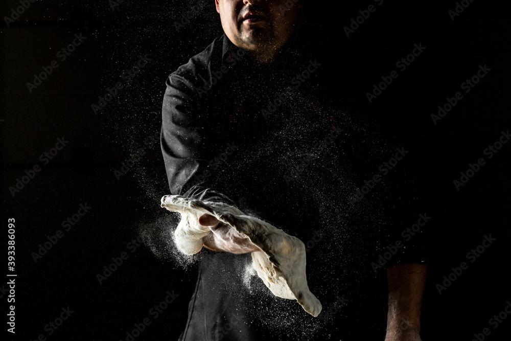 Chef hands cooking dough on dark background. chef throwing up dough for pizza. Chef Making dough. flour splash. Cooking bread. Kneading the Dough