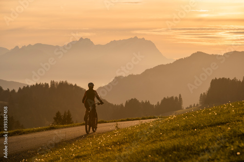 active woman riding her electric mountain bike at sunset in front of the awesome silhouette of Mount Saentis, Appenzell switzerland © Uwe
