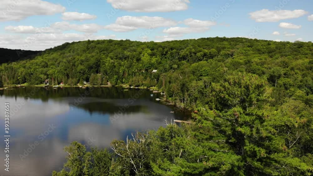 A rising shot over a forest revealing a lake in cottage country. A rising shot over a forest revealing a lake in cottage country.
