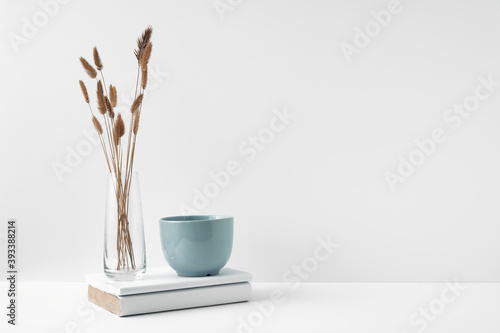 A mug, stack of books and a transparent vase. Eco-friendly materials in interior decor, minimalism. Copy space, mock up photo