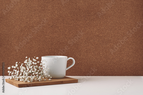 White cup and flowers on a chalkboard, cork background. Mock up, copy space