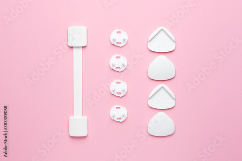 Plug on the electrical outlet and Protection for sharp corners on pink background, baby and children's safety © KatrinaEra