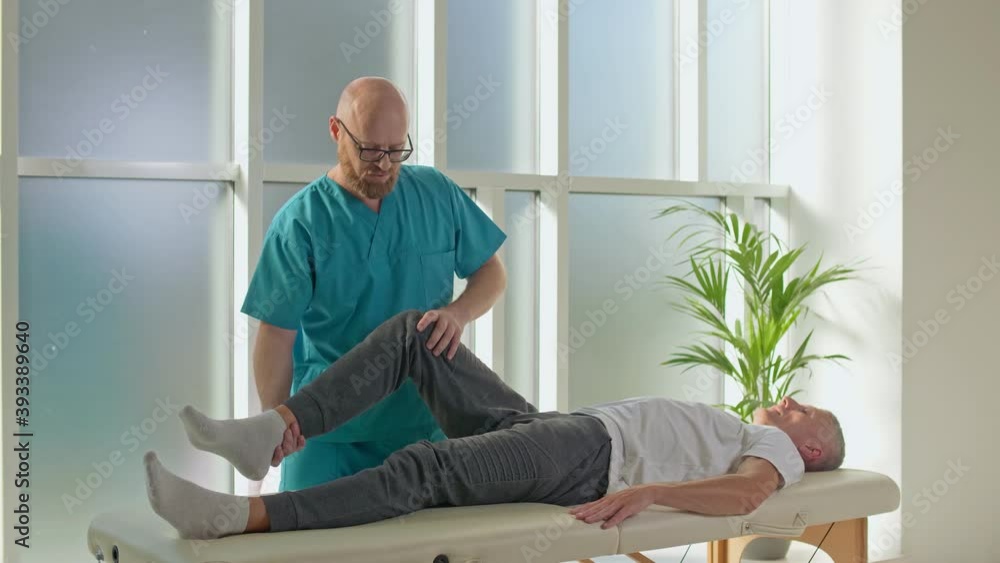 Physiotherapist Conducting a Therapy Session With an Older Man in a Rehabilitation Center. Sports Physiotherapy Concept Physiotherapist Conducting a Therapy Session With an Older Man in a Rehabilitation Center. Sports Physiotherapy Concept