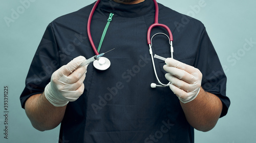 A doctor in professional clothing holds a syringe in his hands. Vaccination, vaccine, medicine, vitamins in medicine. Vaccination against coronavirus.