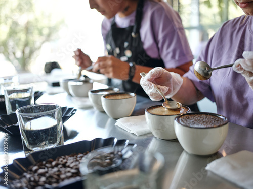 Preparation. Close up shot of barista using two spoons in the process of coffee cupping. Coffee is poured into tasting cups. Tasting helps to identify differences. Selective focus. Horizontal shot