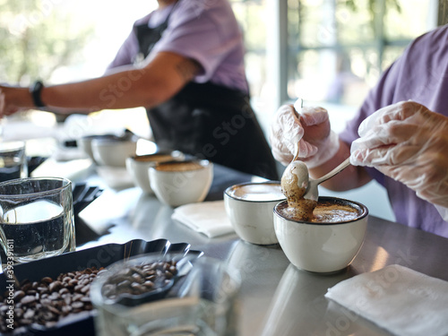 Taste it. Close up shot of barista using two spoons in the process of coffee cupping. Coffee is poured into tasting cups. Tasting helps to identify differences. Selective focus. Horizontal shot
