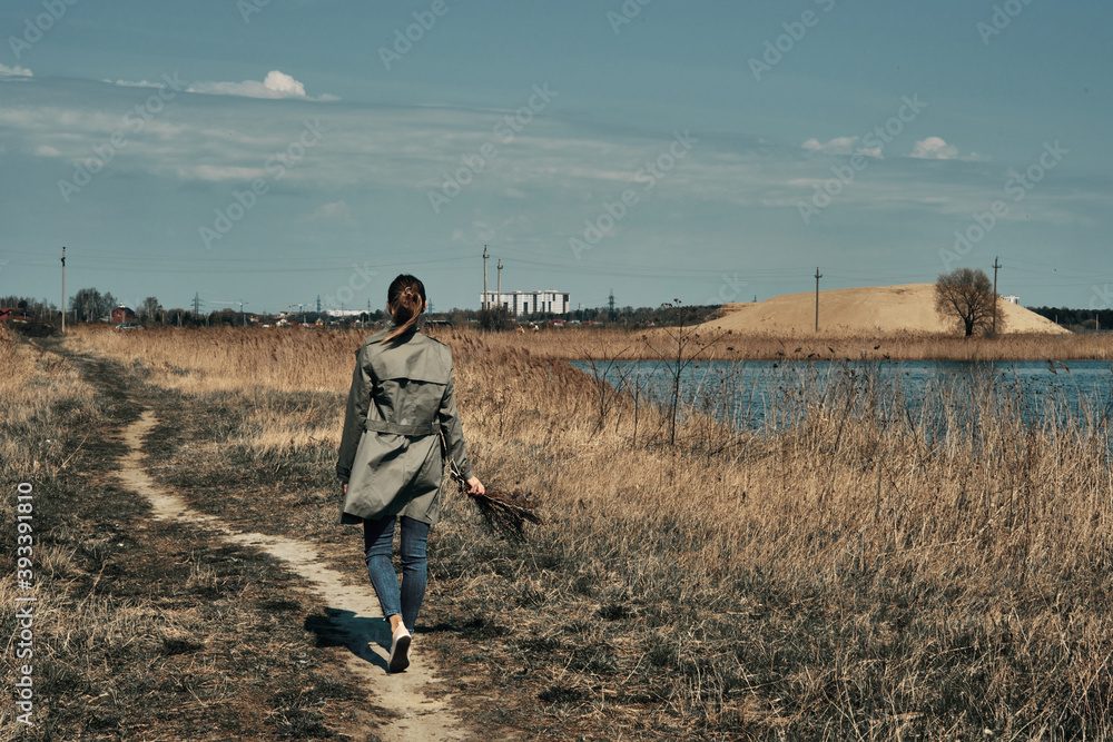 A girl walks along the path, view from the back, autumn A girl walks along the path, view from the back, autumn